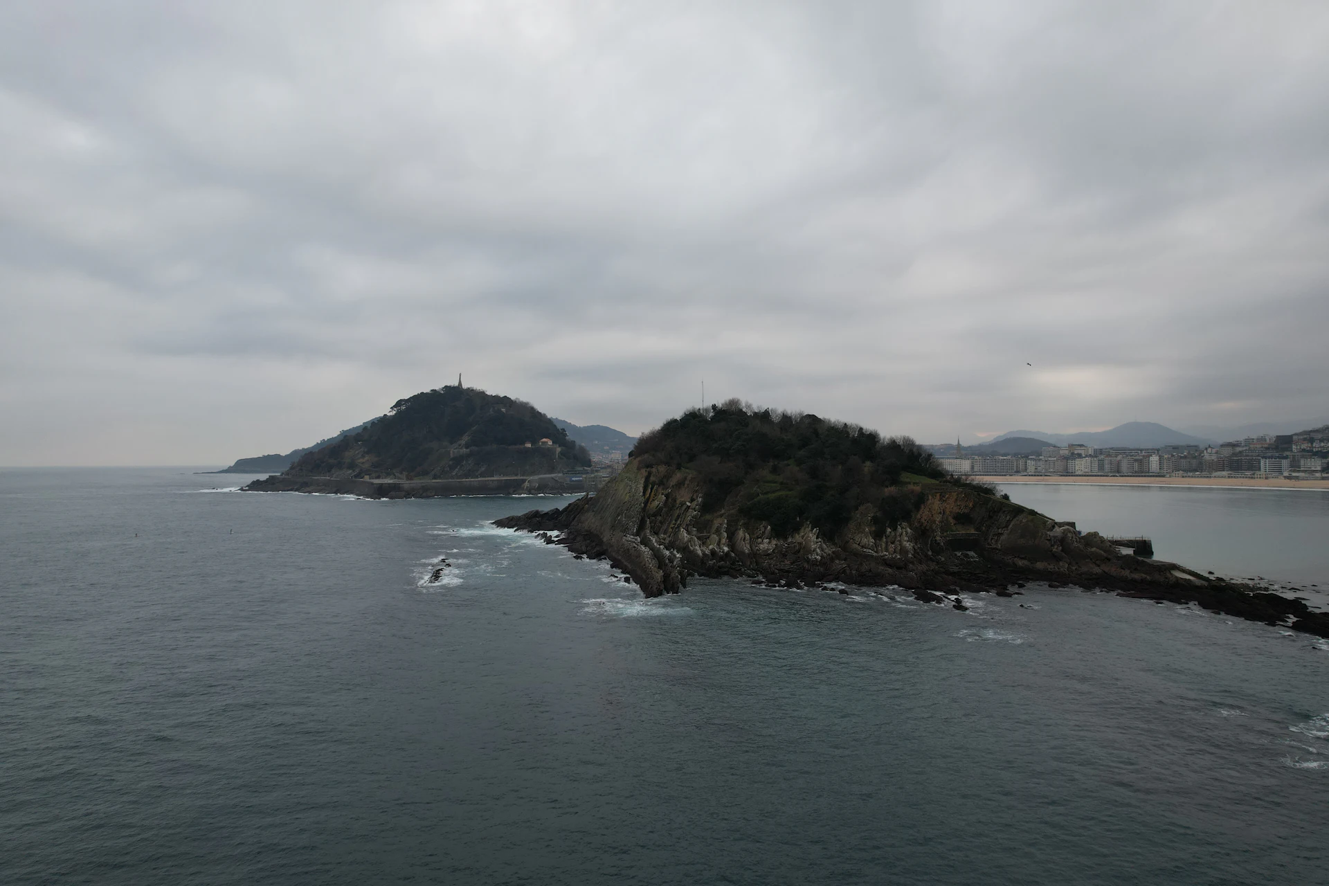 Santa Clara island and Mount Urgull in the bay of Donostia - San Sebastián, under an overcast sky
